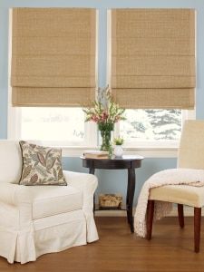 a living room with two chairs and a table in front of the window that has roman shades on it