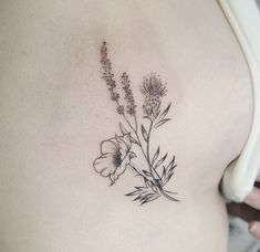 a woman's stomach with flowers and leaves tattoo on her side ribcage