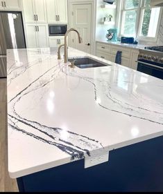 a large kitchen island with marble countertops and white cabinets in the background, along with stainless steel appliances