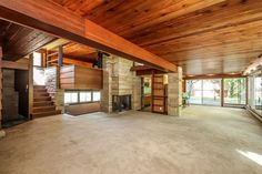 an empty living room with wood paneling and stone fireplace