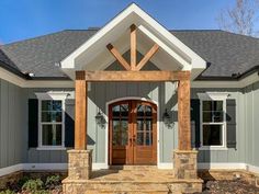 the front entrance to a house with stone steps and pillars on each side, along with an arched wooden door