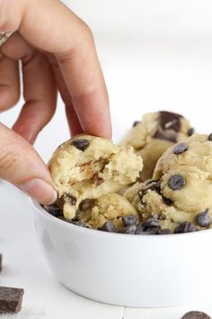 a person scooping chocolate chip cookie dough into a white bowl filled with ice cream