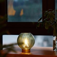 a table with a vase and some plants on it next to a window sill