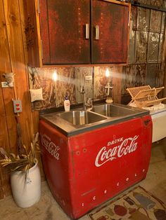 an old coca - cola cooler is sitting in the corner of a room next to a sink