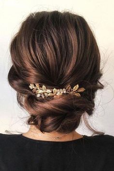 a woman wearing a gold hair comb with leaves on it's side and her hair in a low bun