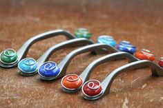 seven different colored metal handles on a wooden surface with the letter q in the middle