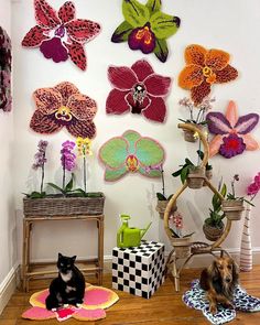 there are many flowers on the wall and one cat is sitting in front of it