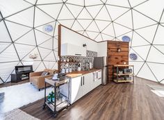 the interior of a yurt with wood floors and white walls, including a kitchen