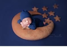 a baby sleeping on the moon with stars around it