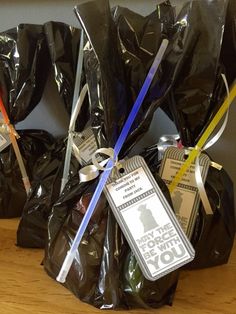 some black bags with tags on them sitting on a wooden table next to each other