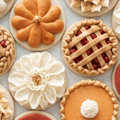 many different types of pies and pastries are arranged on a white tablecloth