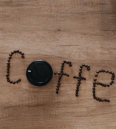 the word coffee spelled out with coffee beans on a wooden table next to a remote control