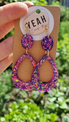 a pair of pink and purple earrings with sprinkles hanging from it's ear