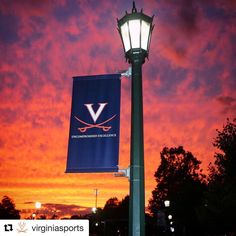 a lamp post with a banner hanging from it's side at sunset or dawn