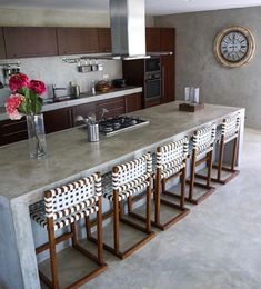 a kitchen counter with chairs and a clock on the wall