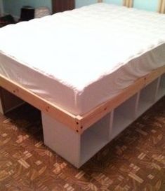 a bed that is made up with some drawers underneath it and the mattress has been pulled out