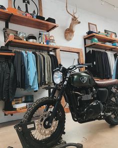 a motorcycle parked inside of a shop next to shelves with shirts on them and deer head