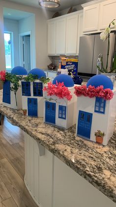 four house shaped boxes sitting on top of a counter in front of a kitchen island