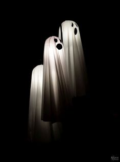 three white plastic ghost heads in the dark