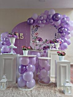 balloons and vases are on display in front of a purple backdrop with white pillars