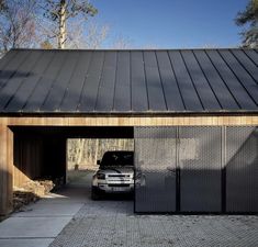 a car is parked in front of a garage with a metal roof and black gate