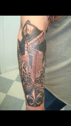 a man with a black and grey tattoo on his arm that says bourbon in front of a cityscape