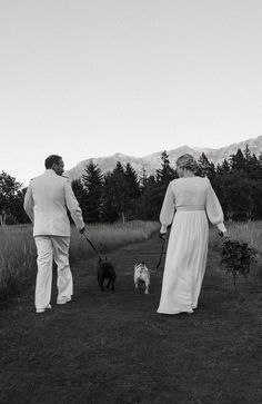 a man and woman walking their dogs in the grass