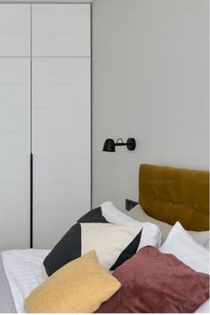 a bedroom with a bed, closet and pillows on it's side in front of a white wall