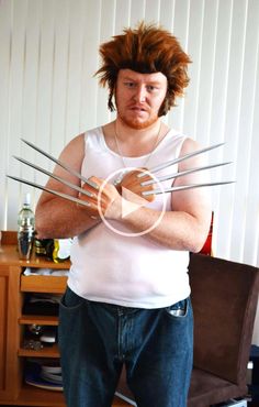 a man with long hair and claws on his chest standing in front of a table