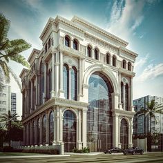 a large white building sitting next to a palm tree on a city street in front of tall buildings