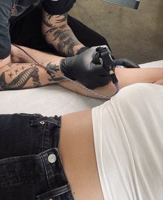 a woman getting her tattoo done by a man with tattoos on his arm and leg