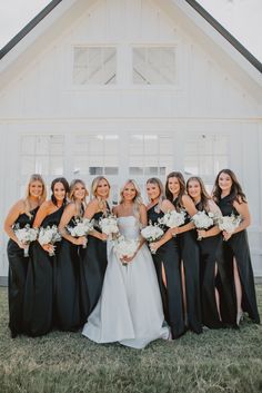 a group of women standing next to each other in front of a white building holding bouquets