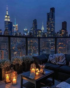 a living room filled with furniture and candles on top of a balcony overlooking the city