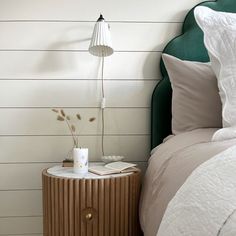 a nightstand with a book on it next to a bed