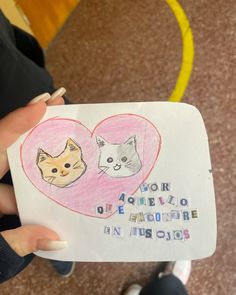 a person holding up a drawing with two cats on it's heart shaped paper