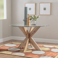 a glass table sitting on top of a wooden floor next to a vase filled with flowers