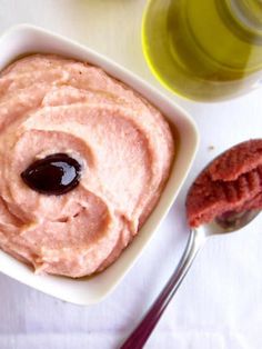 a bowl of hummus with a spoon next to it on a white tablecloth