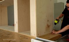 a man using a power drill to attach plywood boards in a room that is being built