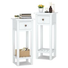 two white side tables with baskets and flowers on them, one has a book shelf next to the other