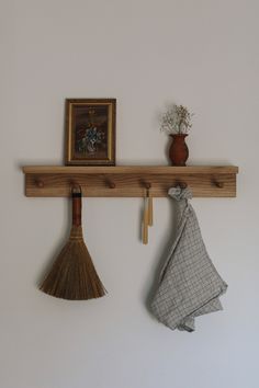 two brooms are hanging on the wall next to a potted plant and a painting