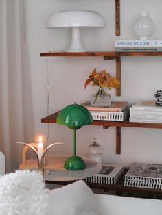 a green lamp sitting on top of a table next to a book shelf filled with books