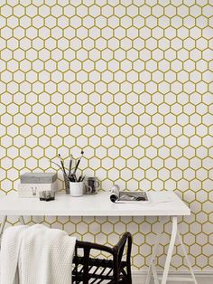 a white table sitting next to a wall with yellow hexagonal tiles on it