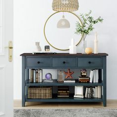 a blue shelf with books and vases on it in front of a white wall