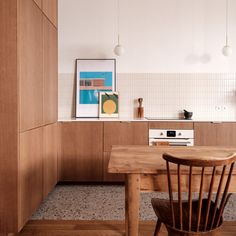 a wooden table and chairs in a room with white tiles on the walls, and wood cabinets