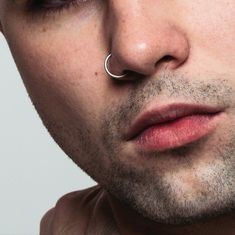 a man with piercings on his nose looking at the camera while wearing a ring