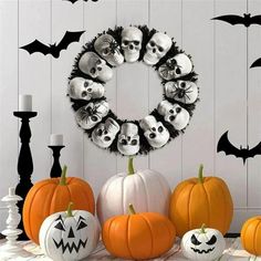 a table topped with lots of pumpkins next to a wreath filled with skulls and bats