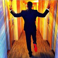 a man in a suit and red socks is walking down the hallway with his hands up