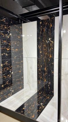 a black and white bathroom with marble tiles on the wall, shower stall door and floor