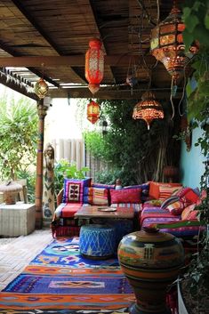 an outdoor living area with lots of colorful pillows and rugs on the floor,