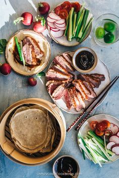 an assortment of food on plates and bowls with chopsticks next to each other